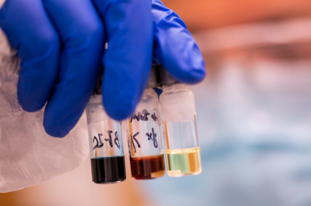 Yongxi Li holds up vials containing the polymers used to make the transparent solar cells. Image credit: Robert Coelius, Michigan Engineering Communications & Marketing